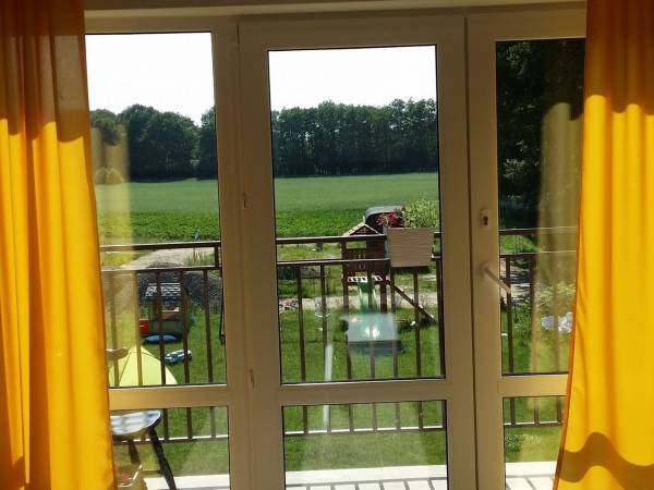 Widok z apartamentu słonecznego na piętrze na plac zabaw i w oddali las.