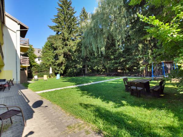 Ogród z zejściem do rzeczki otoczony zielenią i drzewami.