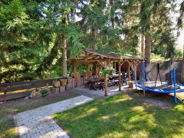 Domek do grillowania z kominkiem, za drzewami płynąca rzeczka Bystrzyca Dusznicka.