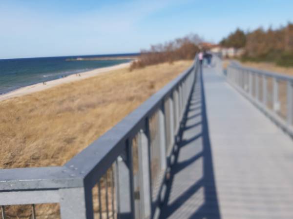 Kładka przyrodncza z widokiem na plażę i morze.