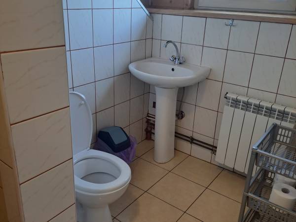 Łazienka w pokoju dwuosobowym z dwoma oddzielnymi łóżkami w żółtym budynku 